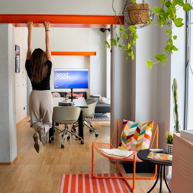 Alessandra del team appesa alla trave arancione dell'open space dello studio GOODCOM