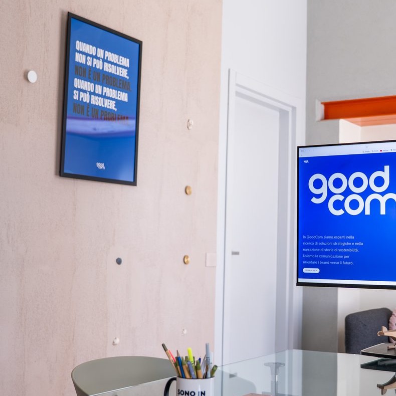 Poster con una citazione e schermo con il logo GOODCOM nello studio