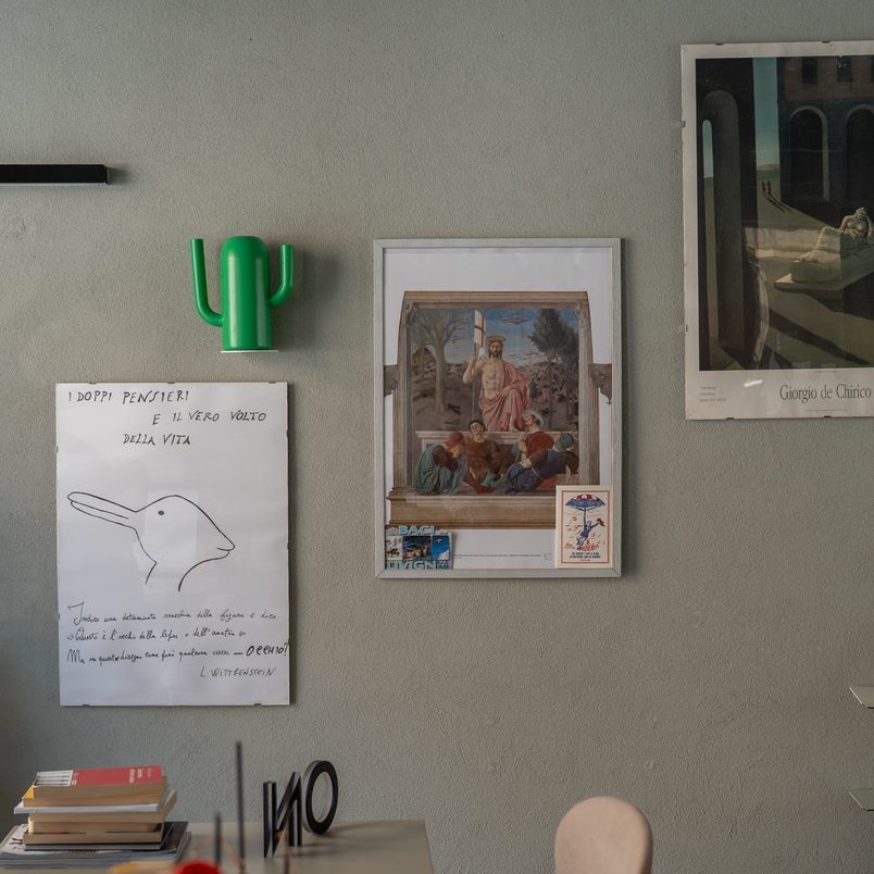 Parete dello studio GOODCOM con stampe d'arte, un disegno a mano e un appendiabiti a forma di cactus