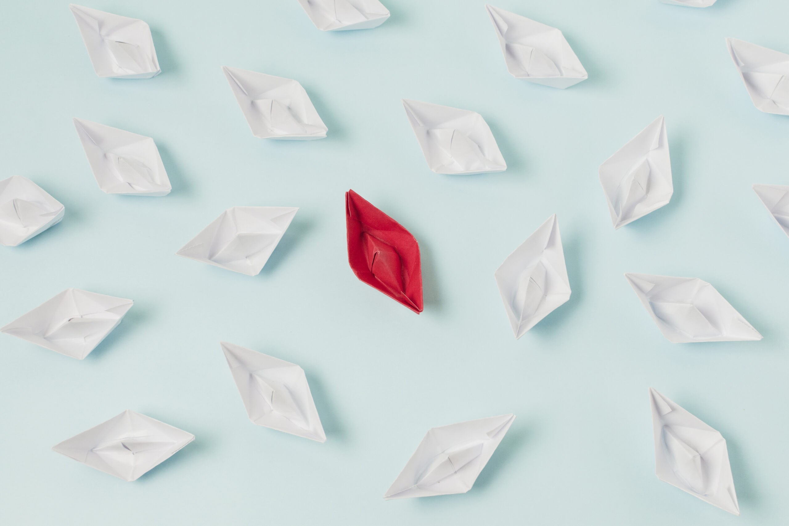 Barchetta di carta rossa tra barchette bianche, simbolo del brand purpose