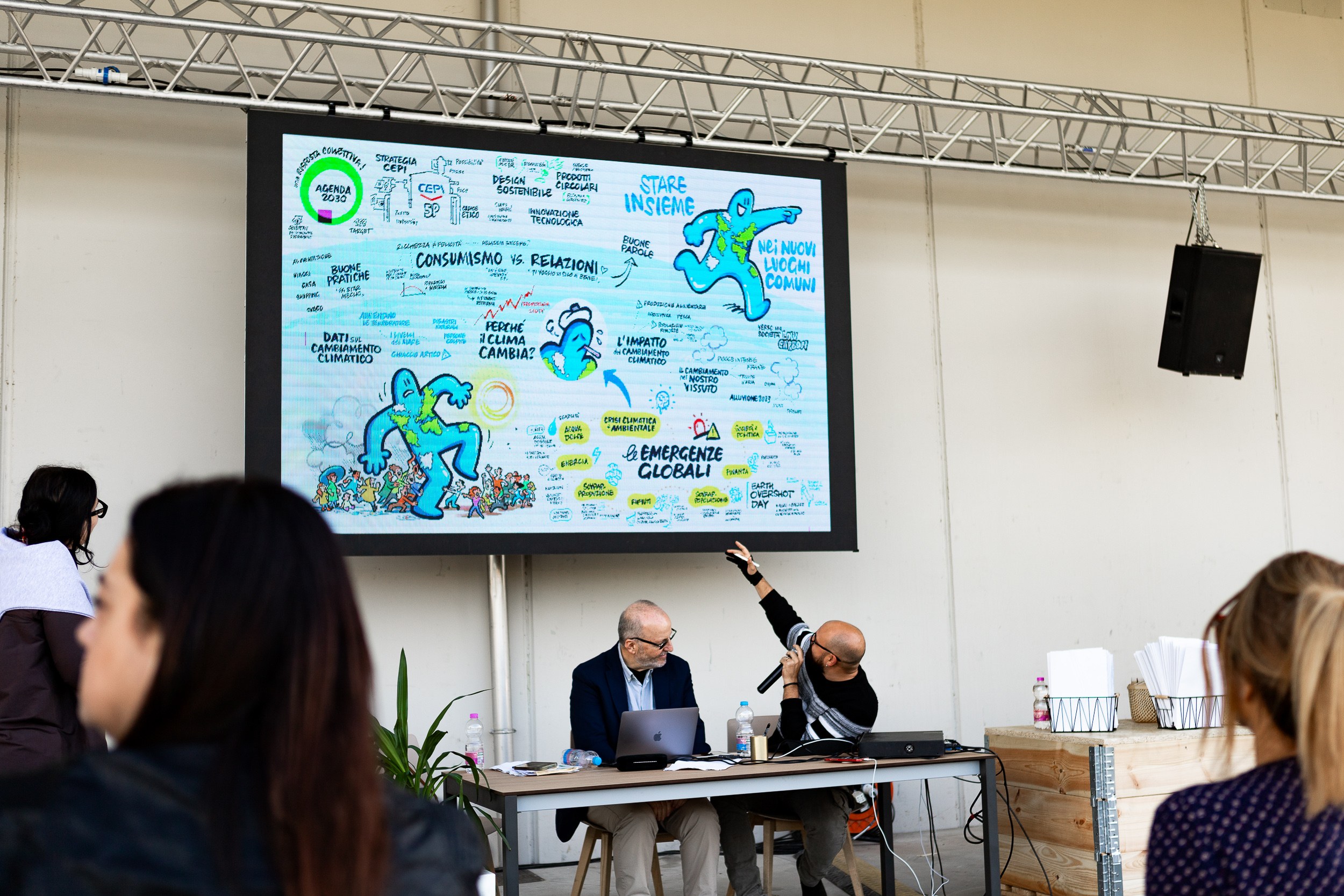 Convegno su progetti ESG con relatori al tavolo e schermo con una mappa illustrata