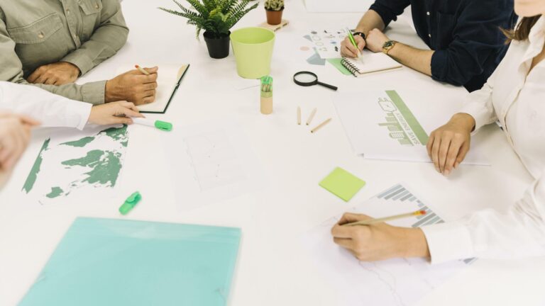Gruppo di lavoro su grafici e appunti di sostenibilità aziendale sparsi su un tavolo
