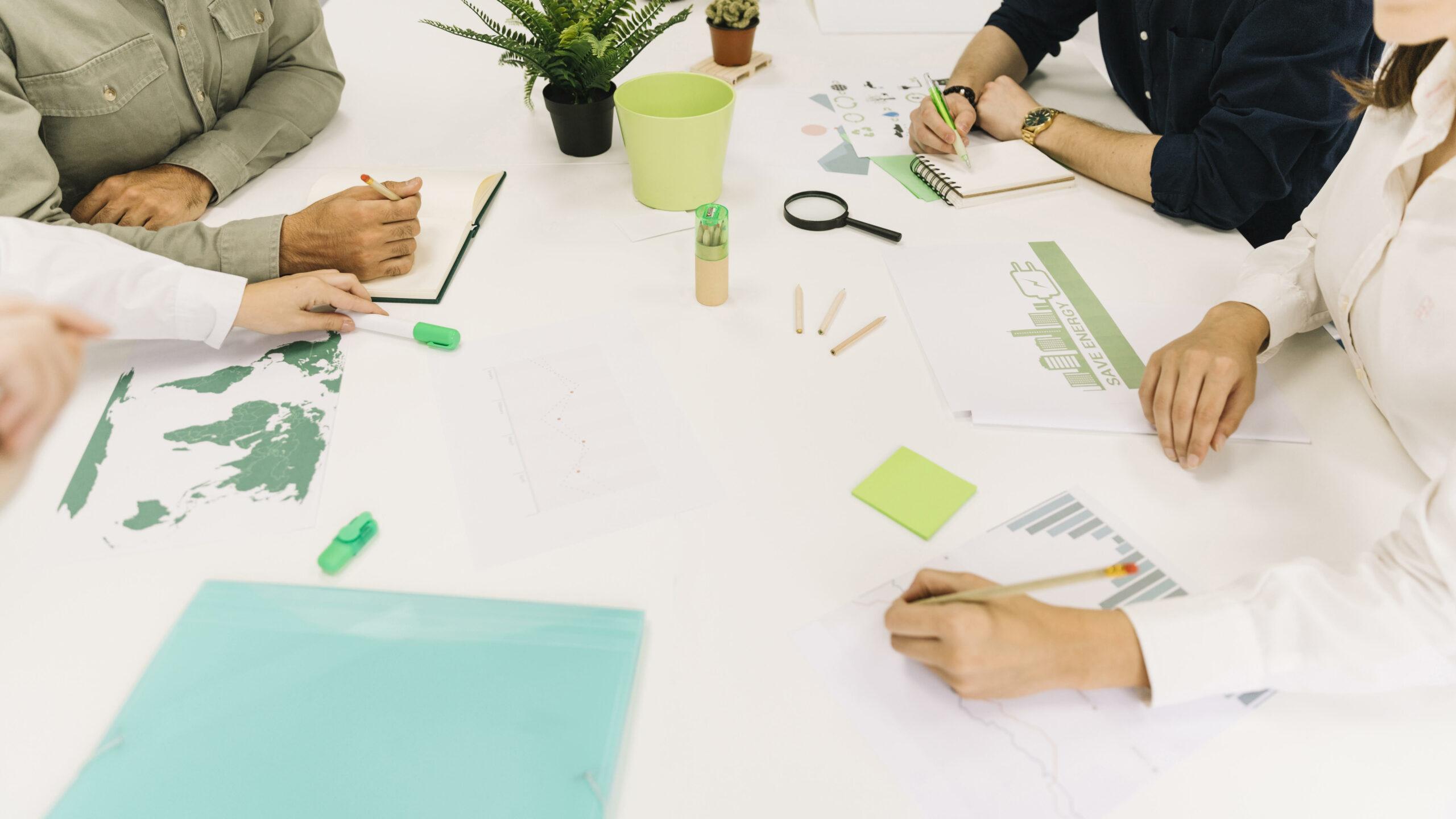 Gruppo di lavoro su grafici e appunti di sostenibilità aziendale sparsi su un tavolo