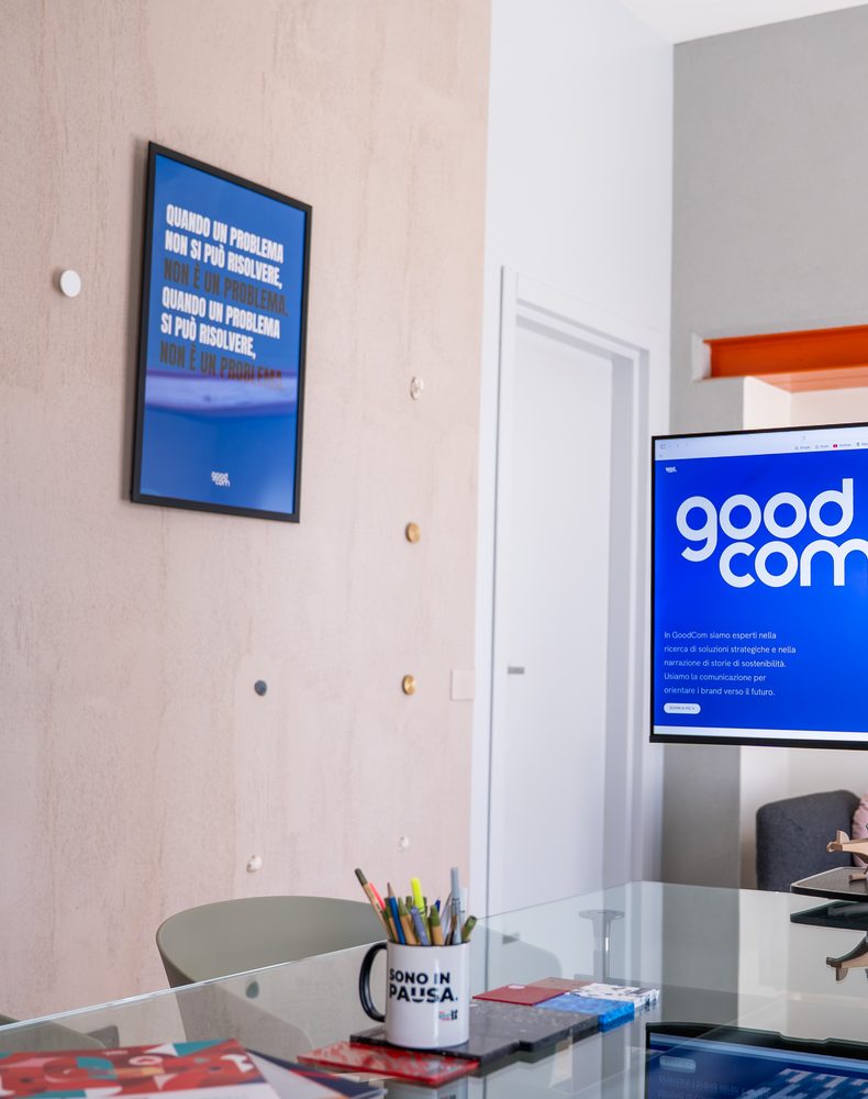 Poster con una citazione e schermo con il logo GOODCOM nello studio