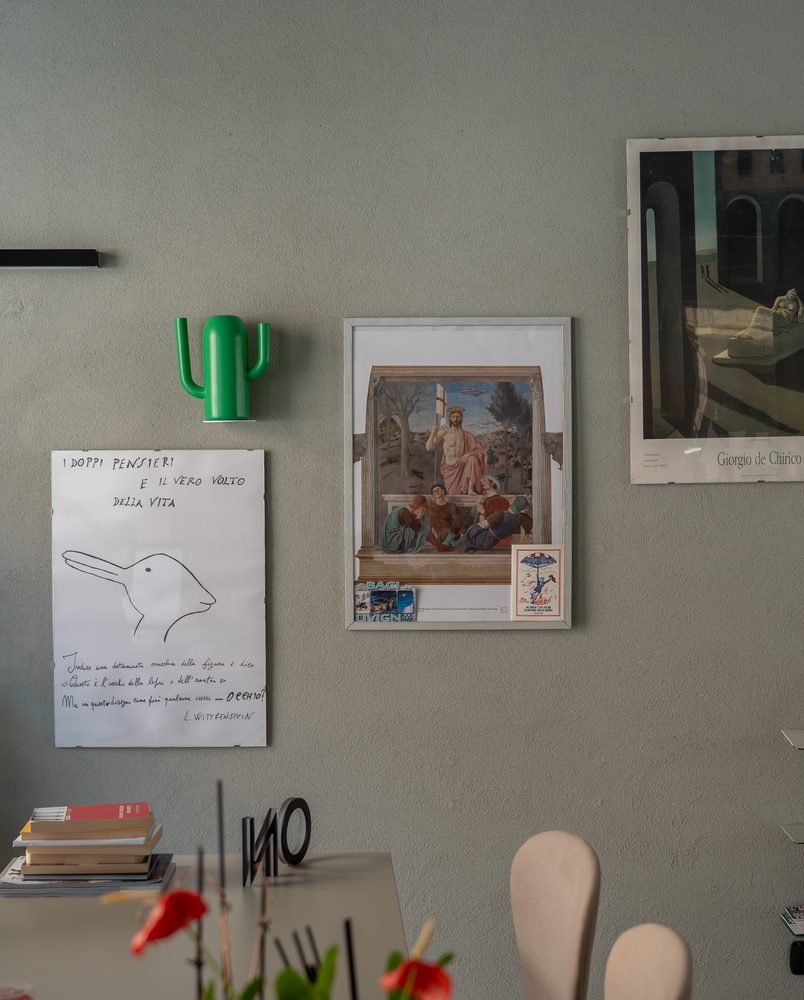 Parete dello studio GOODCOM con stampe d'arte, un disegno a mano e un appendiabiti a forma di cactus