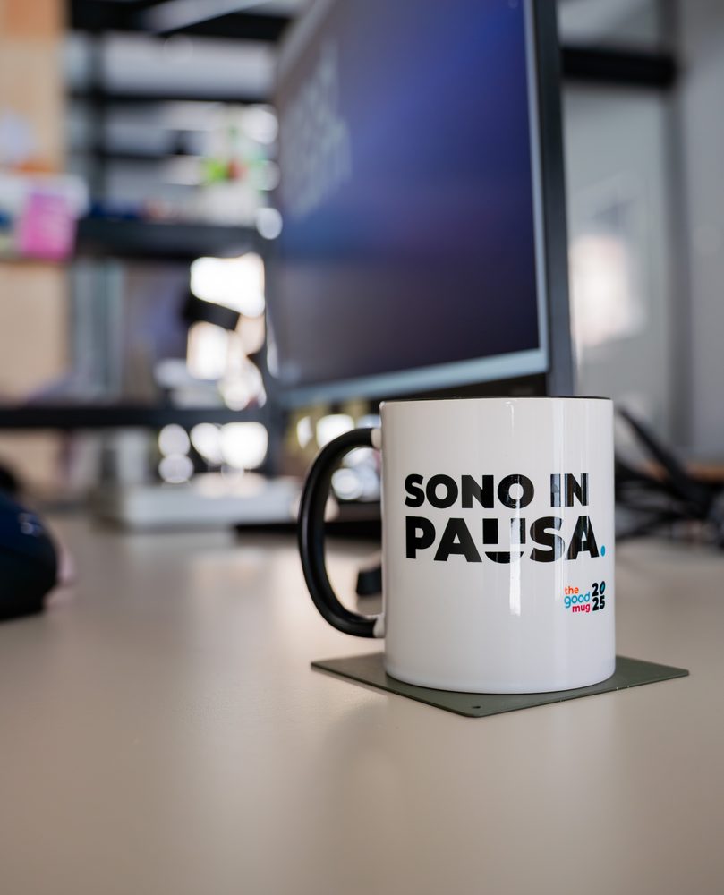 Tazza con la scritta Sono in pausa su una scrivania dello studio GOODCOM