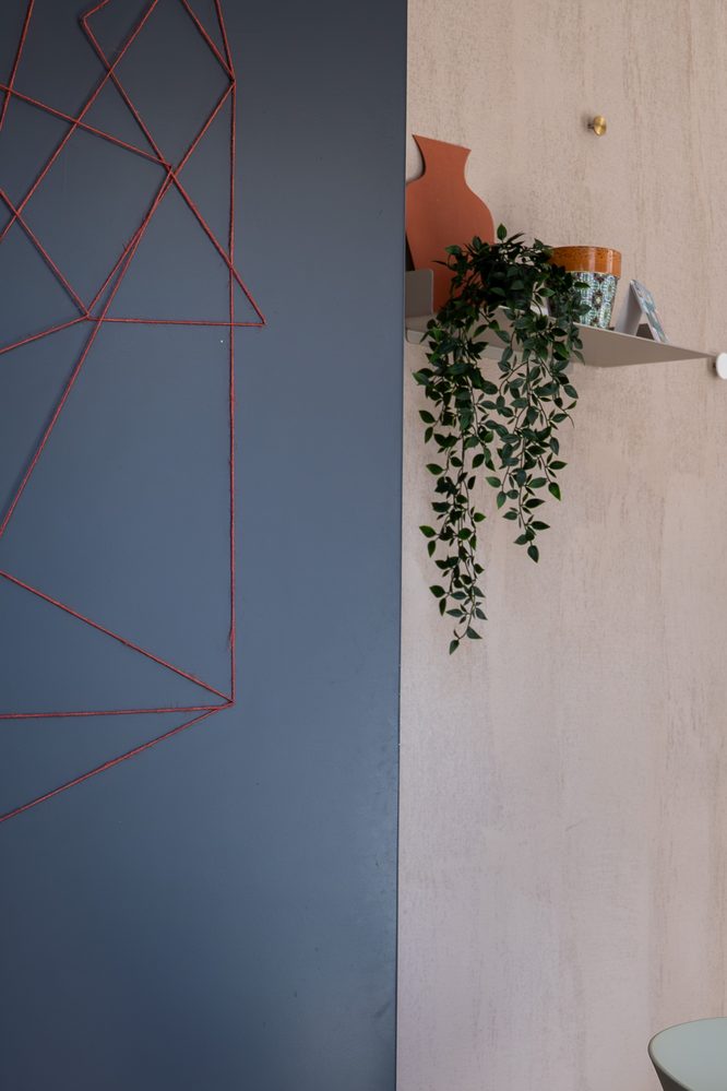 Parete blu con decorazione geometrica e mensola con una pianta nello studio GOODCOM