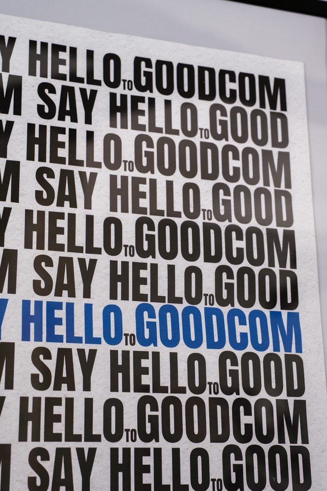 Poster tipografico con la scritta Say hello to GOODCOM ripetuta su più righe
